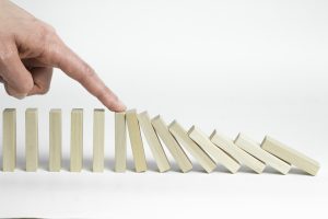 A finger pointing at a domino effect
